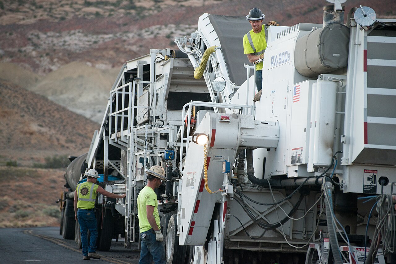 Crew working beside a cold-in-place recycling train on a rural road
